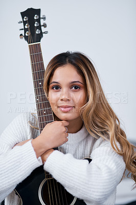 Buy stock photo Cropped shot of a young woman sitting at home with her guitar