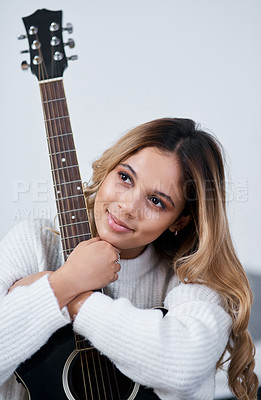 Buy stock photo Cropped shot of a young woman sitting at home with her guitar