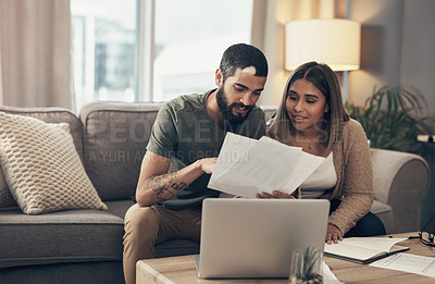 Buy stock photo Shot of a young couple using a laptop while going through paperwork at home