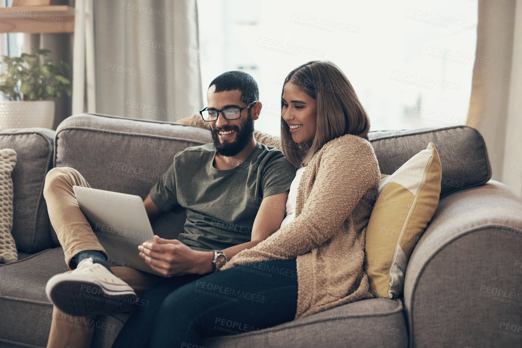 Buy stock photo Shot of a young couple using a laptop on the sofa at home