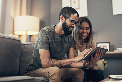 Buy stock photo Shot of a young couple using a digital tablet on the sofa at home