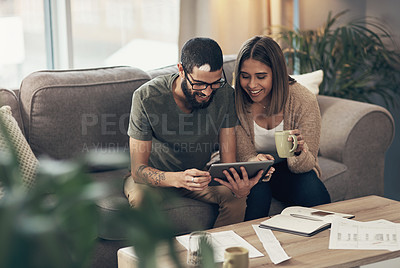 Buy stock photo Shot of a young couple sing a digital tablet while going through paperwork at home