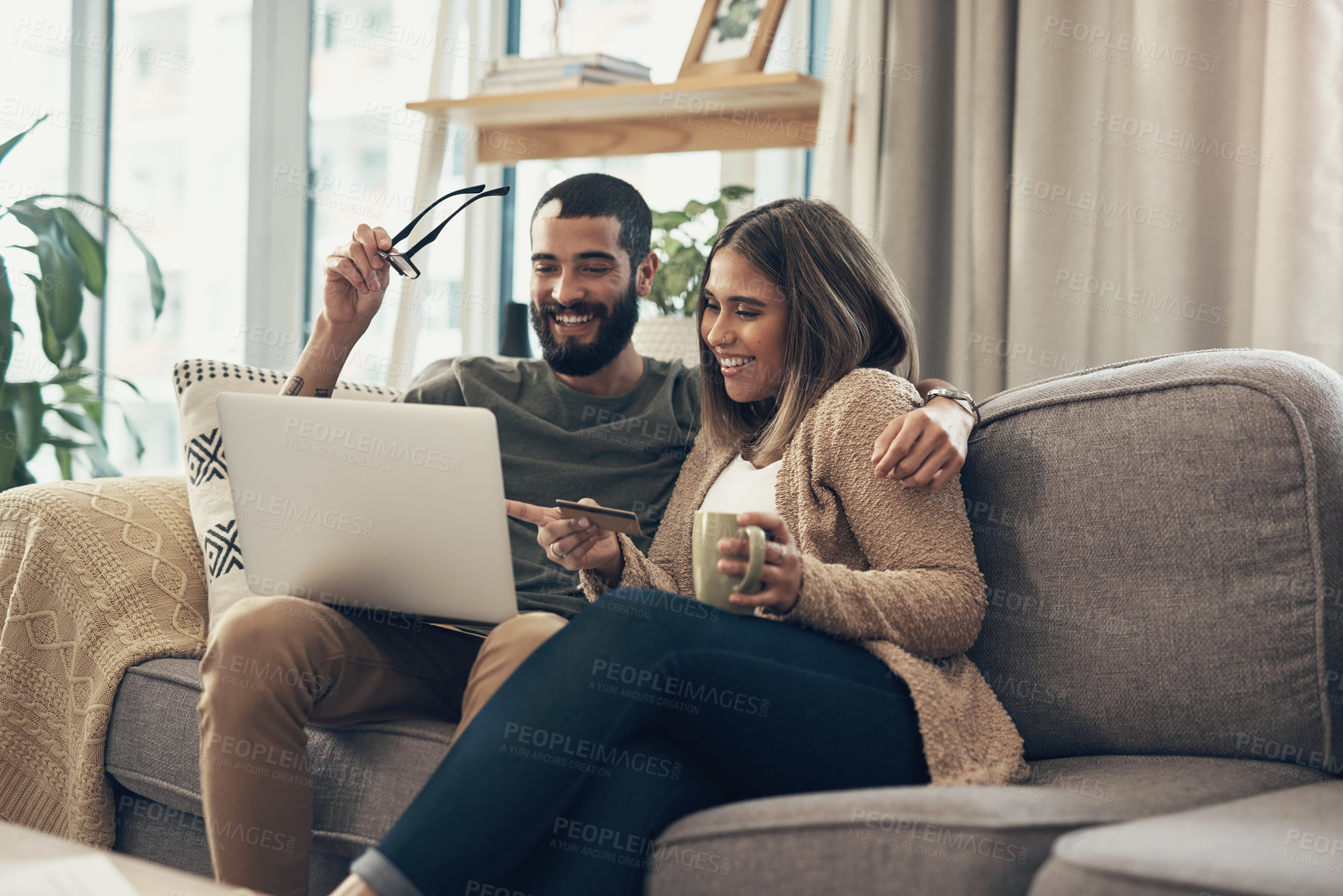 Buy stock photo Shot of a young couple using a laptop and credit card on the sofa at home