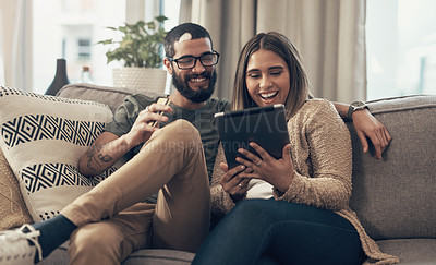 Buy stock photo Shot of a young couple using a digital tablet and credit card on the sofa at home