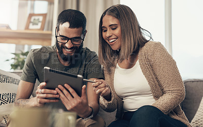 Buy stock photo Shot of a young couple using a digital tablet on the sofa at home