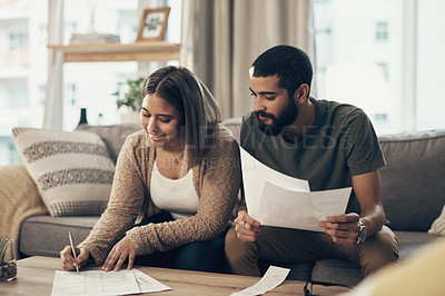 Buy stock photo Shot of a young couple going over paperwork at home
