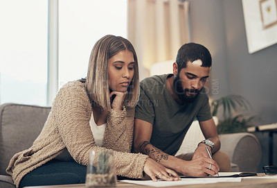Buy stock photo Shot of a young couple going over paperwork at home