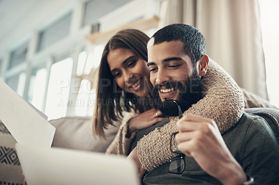 Buy stock photo Shot of a young couple using a laptop while going through paperwork at home
