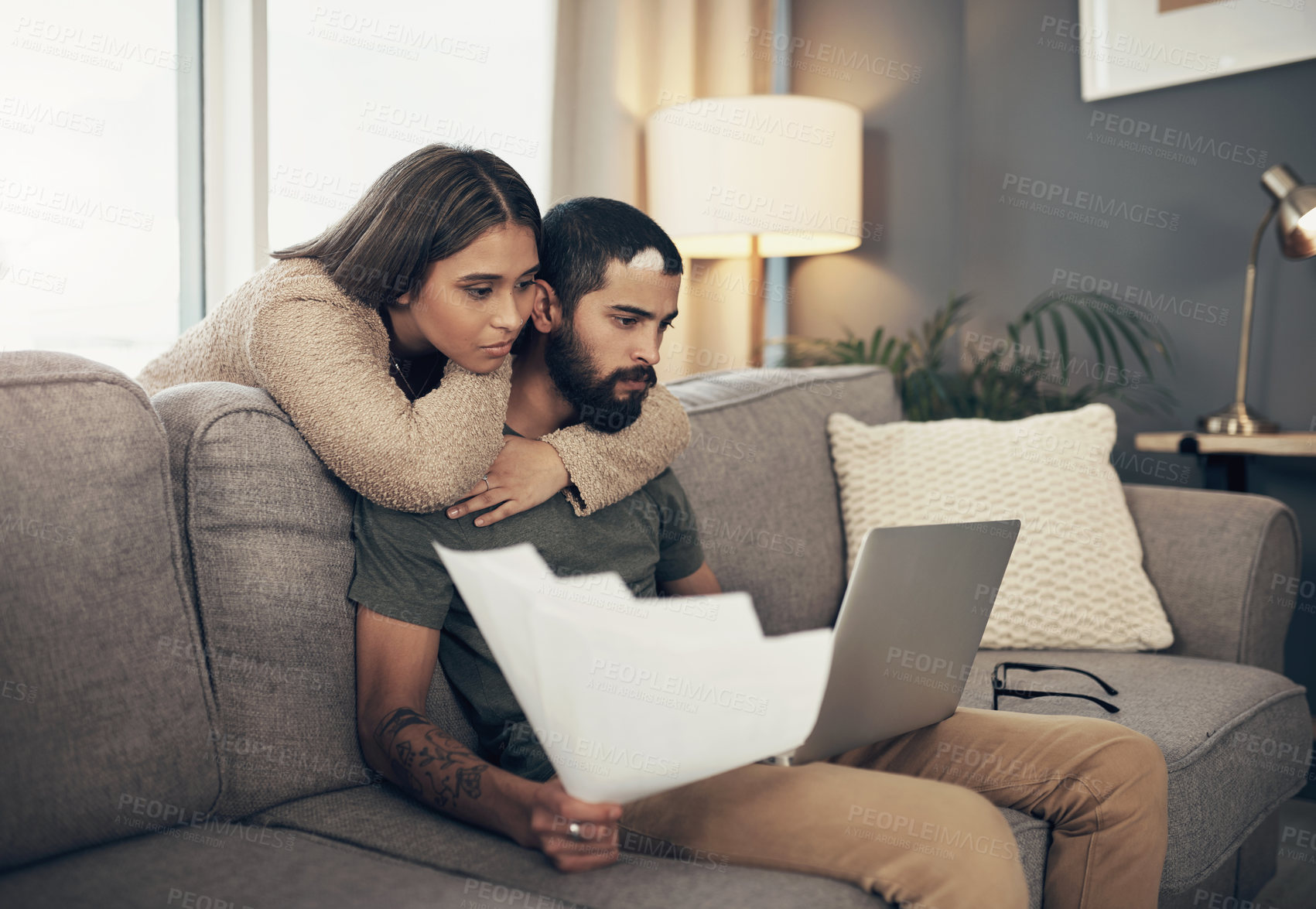 Buy stock photo Shot of a young couple using a laptop while going through paperwork at home