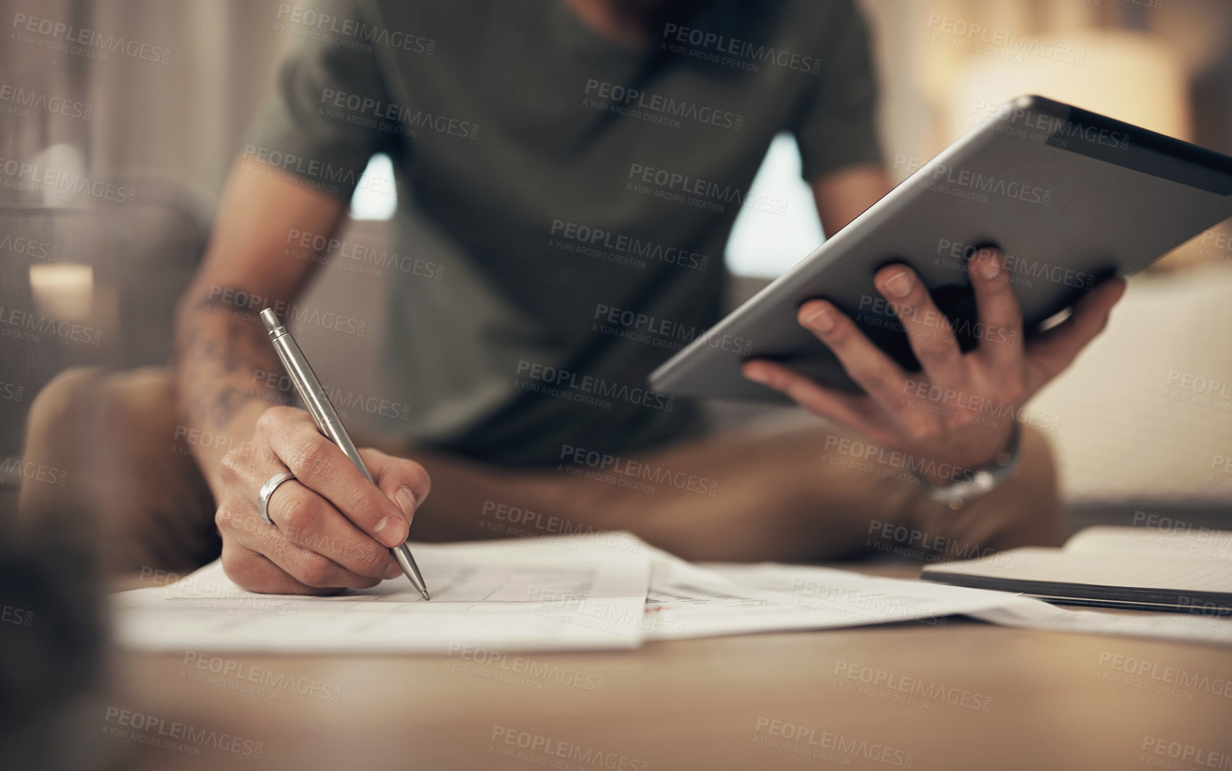 Buy stock photo Cropped shot of a man using a digital tablet while going through paperwork at home