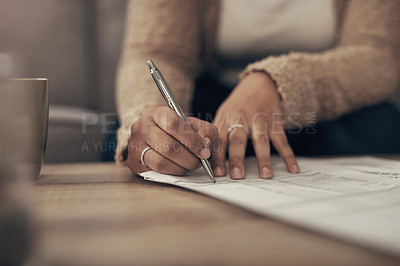 Buy stock photo Cropped shot of an unrecognisable woman going over paperwork at home