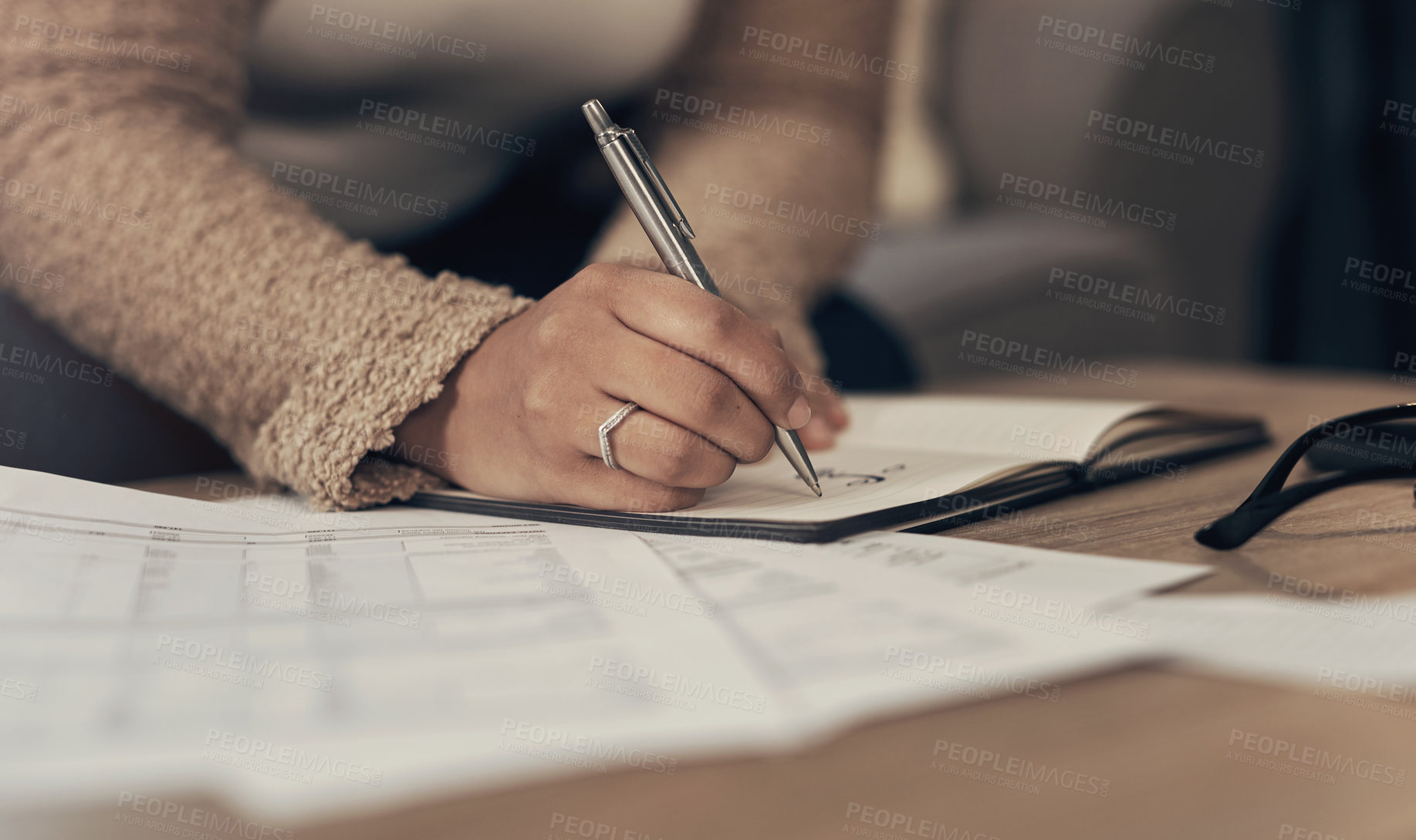 Buy stock photo Cropped shot of an unrecognisable woman going over paperwork at home