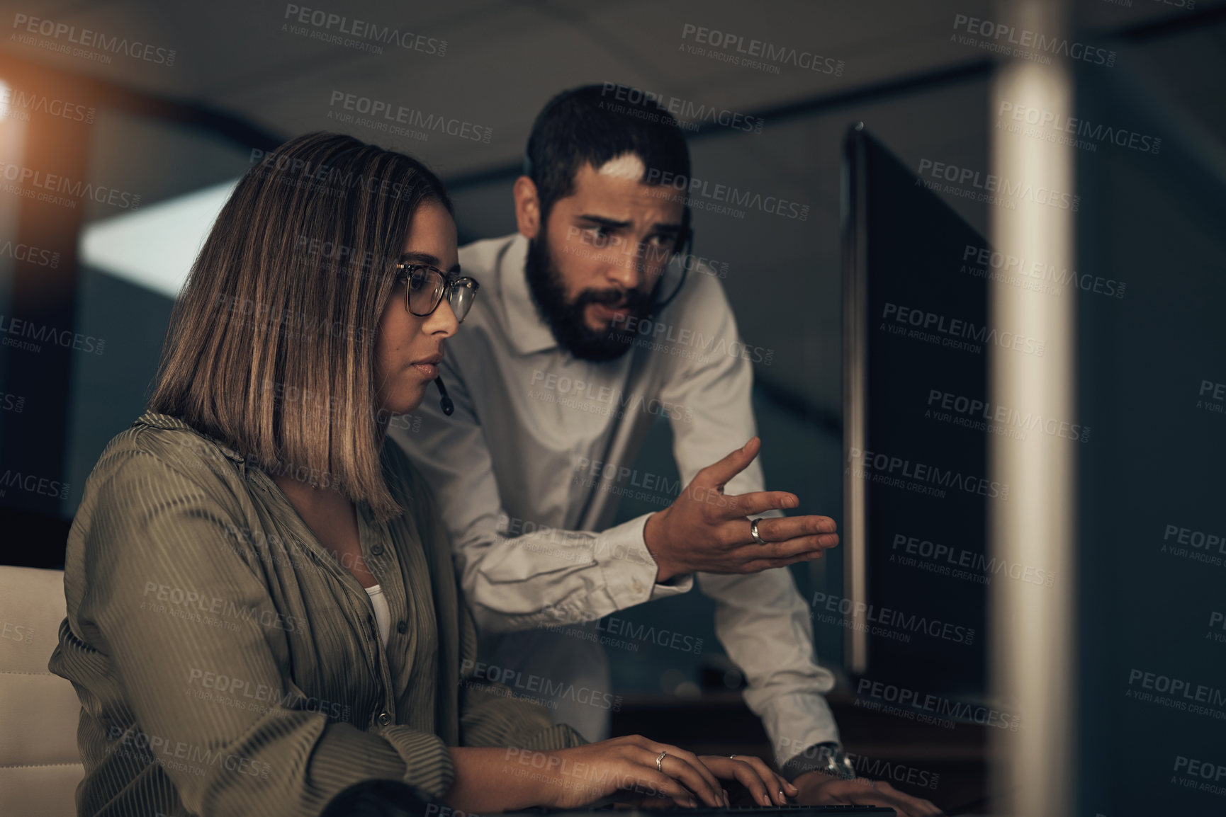 Buy stock photo Shot of two call centre agents working together in an office at night