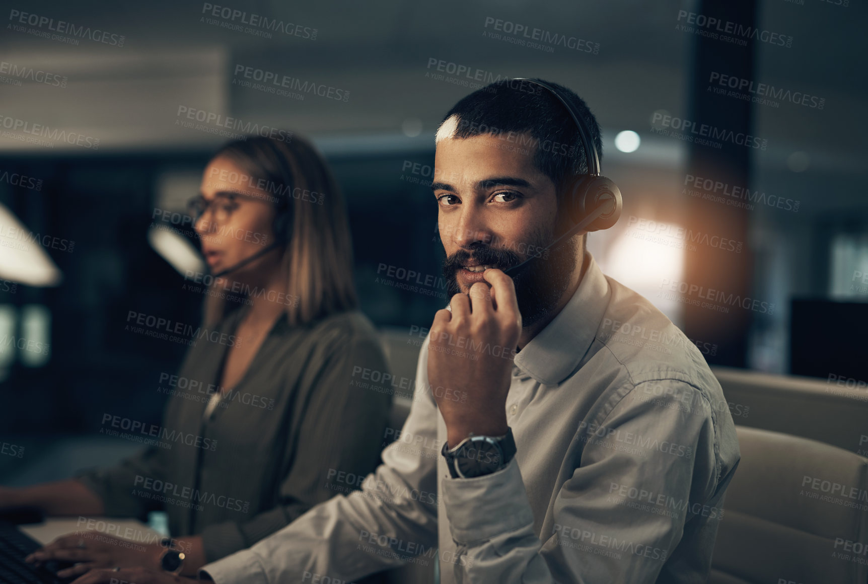 Buy stock photo Portrait of a call centre agent working in an office alongside a colleague at night