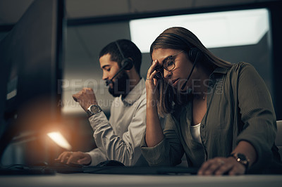 Buy stock photo Shot of a call centre agent looking stressed out while working in an office at night