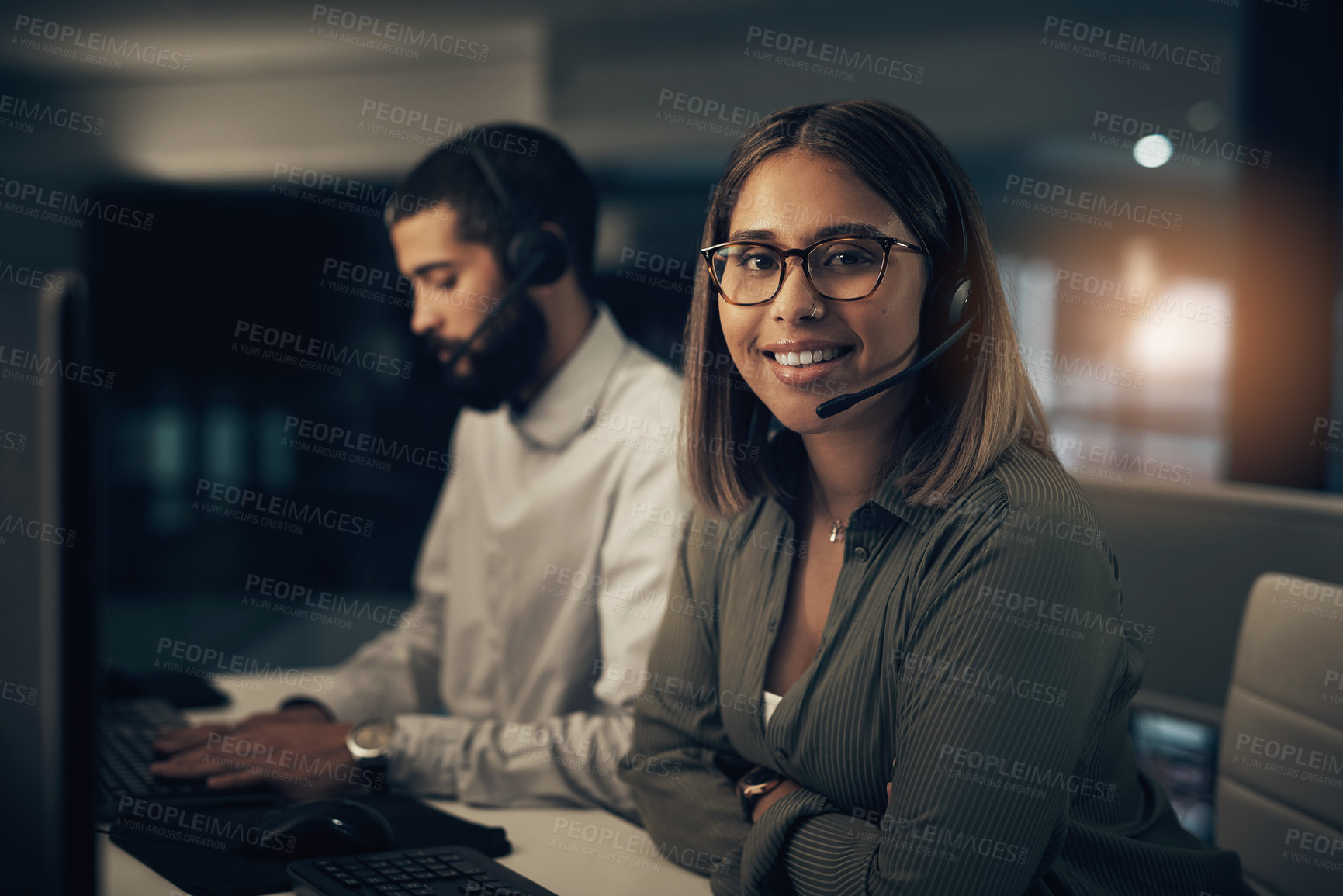 Buy stock photo Portrait of a call centre agent working in an office alongside a colleague at night