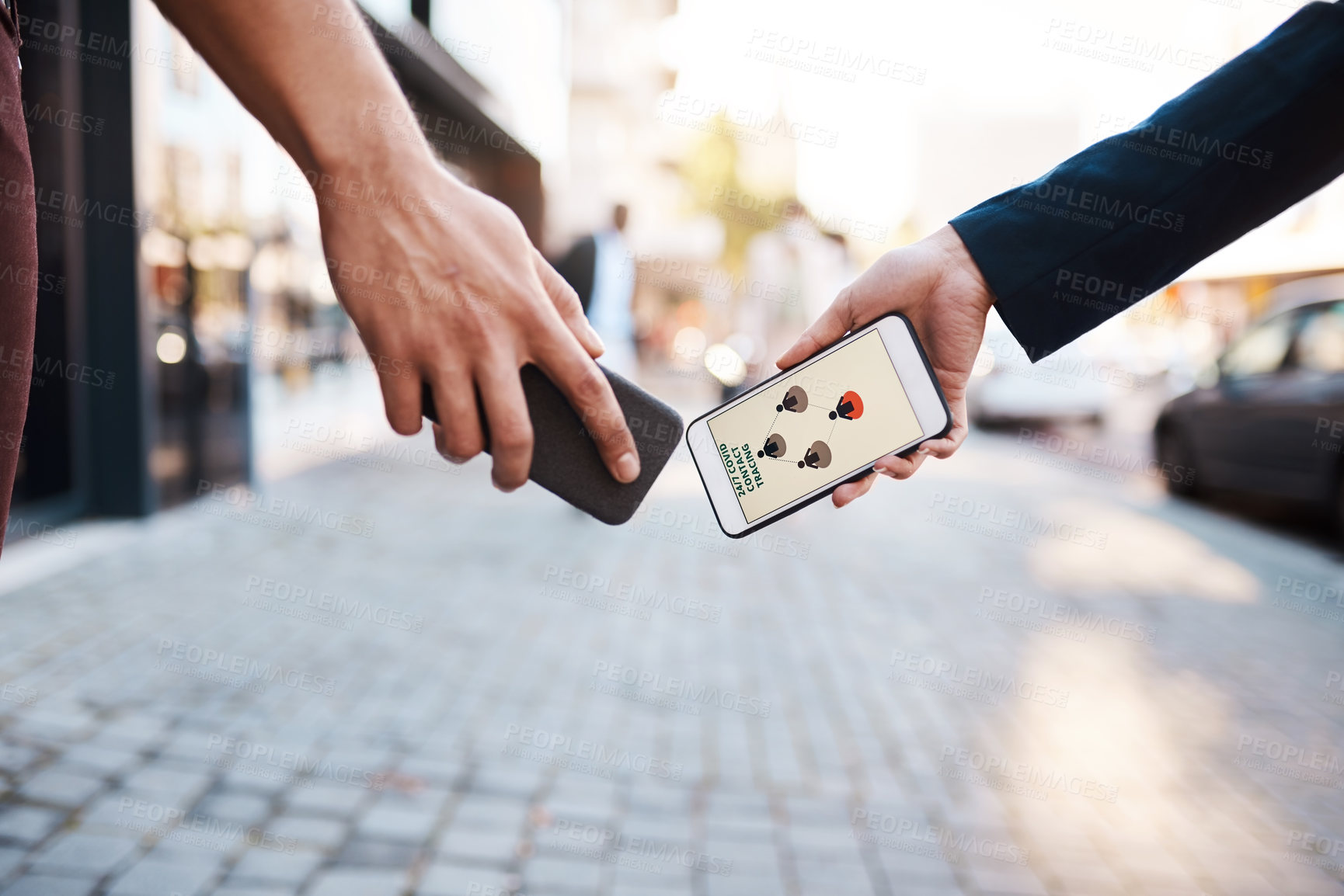 Buy stock photo Shot of two unrecognisable people using Covid-19 tracking apps on their smartphones in the city