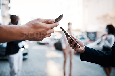 Buy stock photo Shot of two unrecognisable people using Covid-19 tracking apps on their smartphones in the city