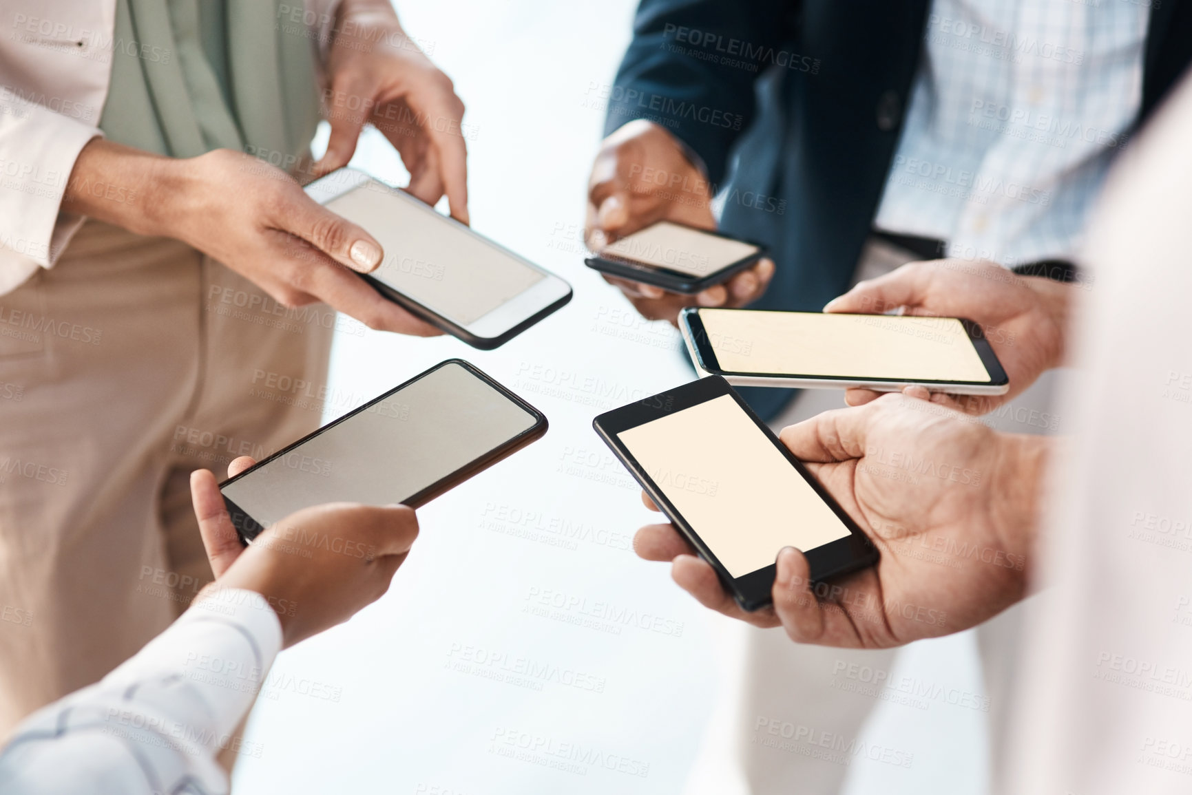 Buy stock photo Shot of a group of unrecognisable businesspeople using their smartphones together