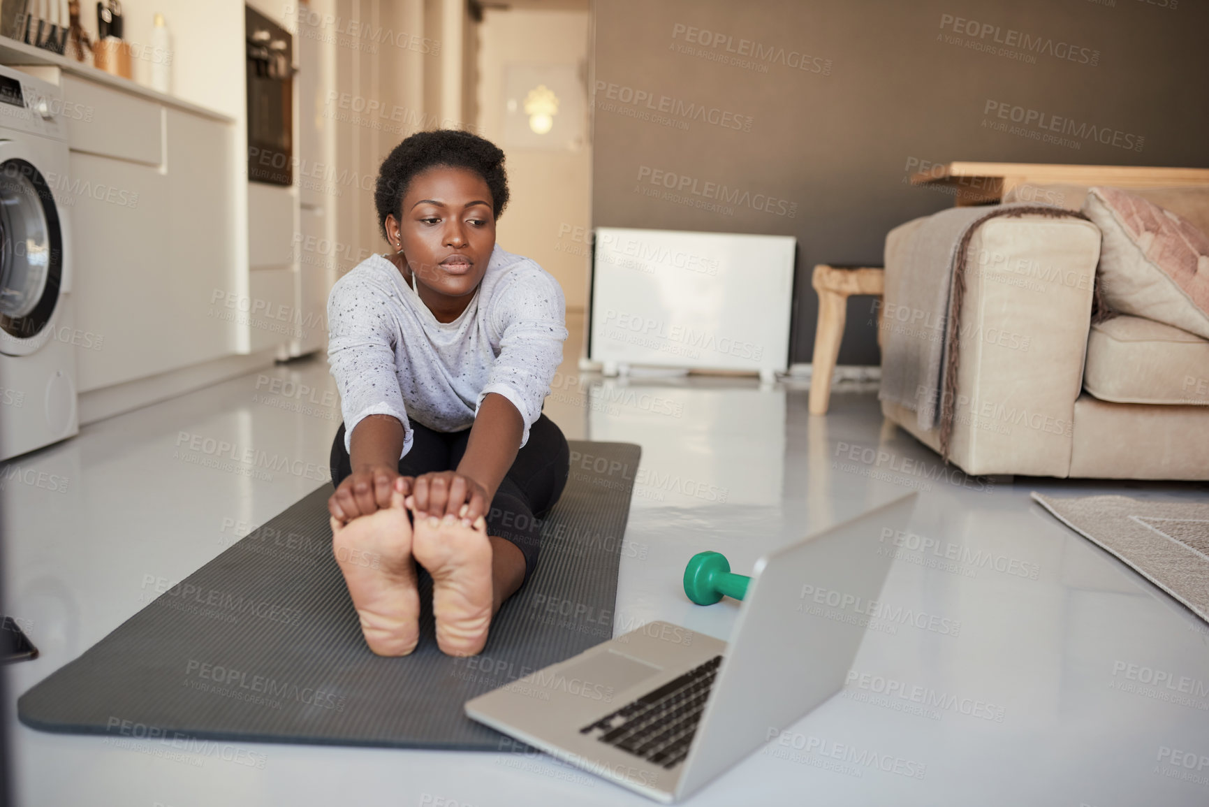 Buy stock photo Shot of a young woman using a laptop while exercising at home