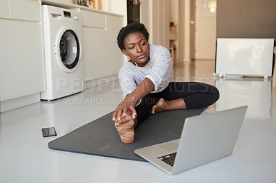 Buy stock photo Shot of a young woman using a laptop while exercising at home