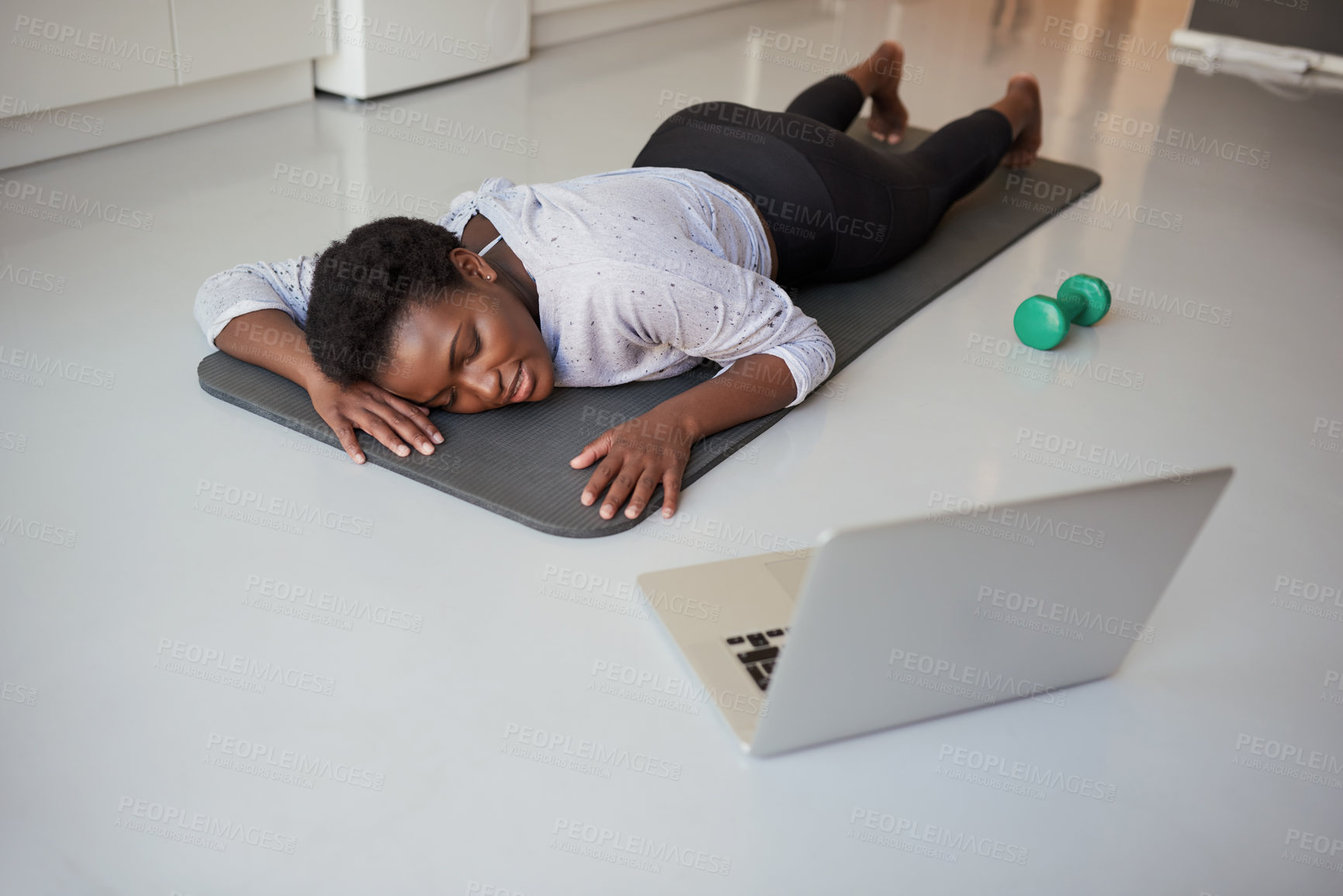 Buy stock photo Shot of a young woman looking exhausted while exercising at home