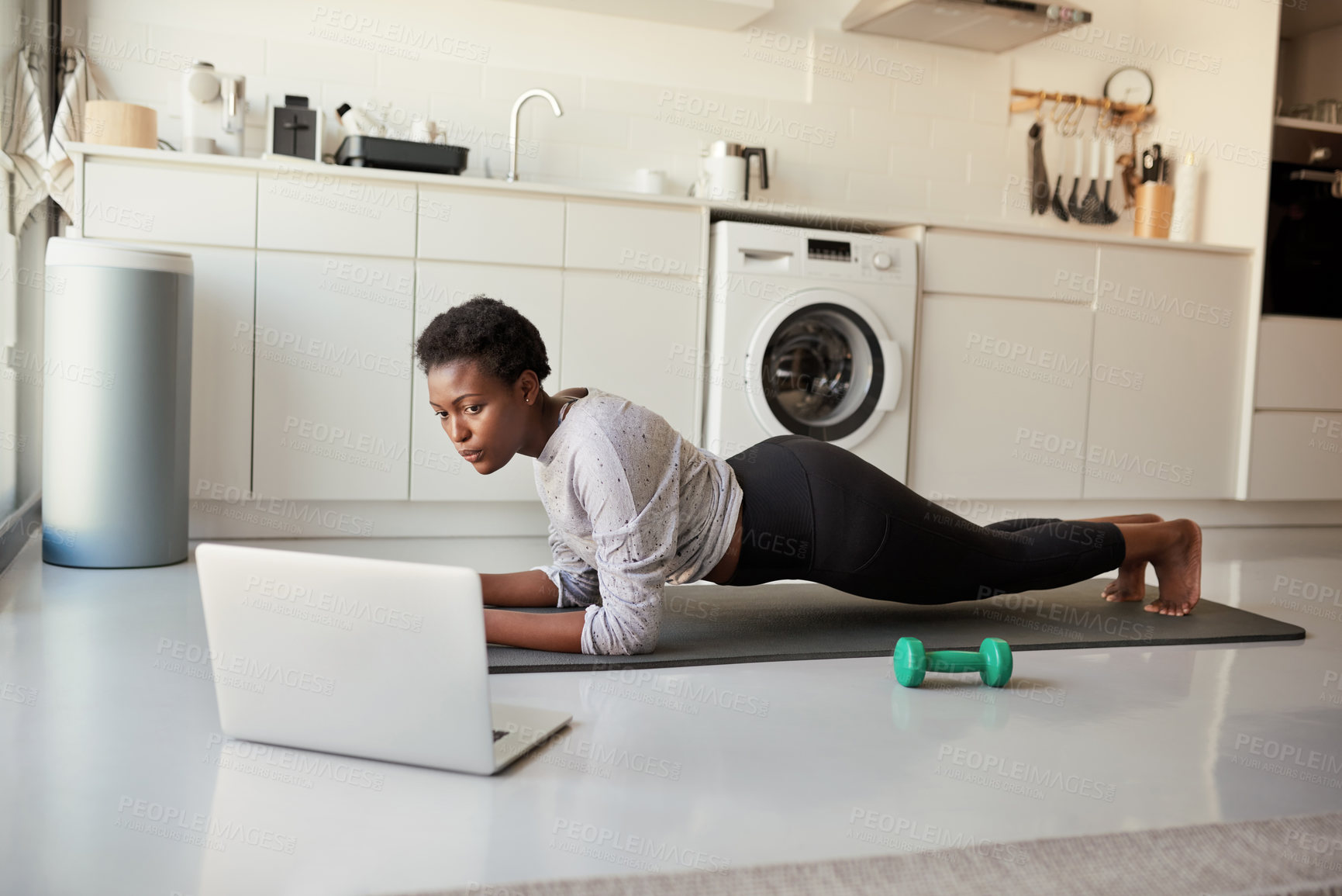 Buy stock photo Shot of a young woman using a laptop while exercising at home