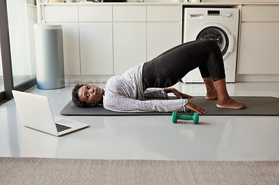 Buy stock photo Shot of a young woman using a laptop while exercising at home