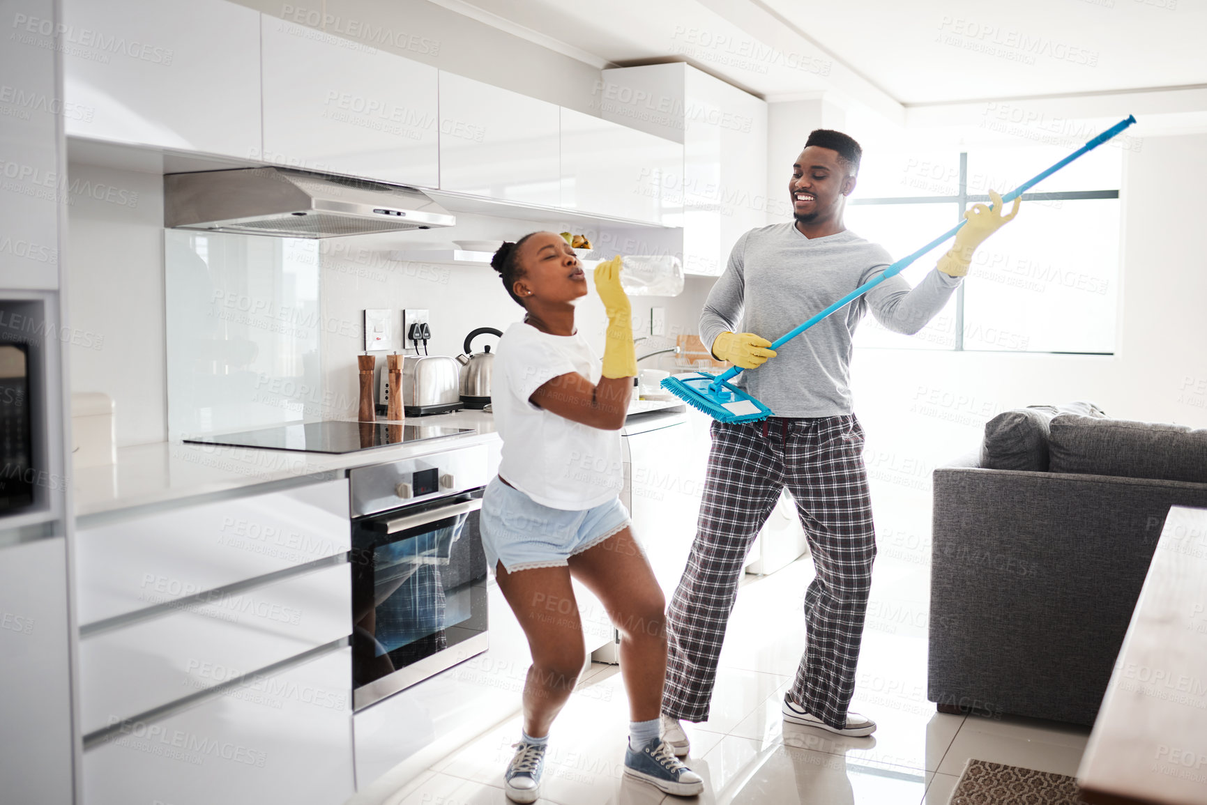 Buy stock photo Shot of a happy young couple having fun while cleaning the kitchen at home