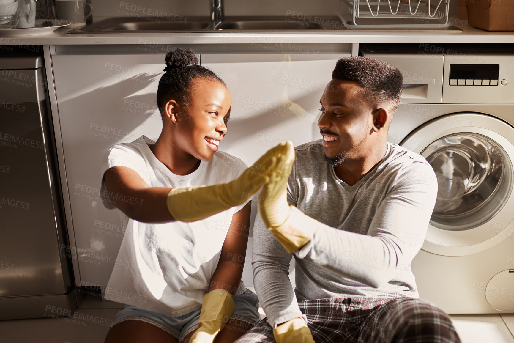 Buy stock photo Shot of a young couple giving each other a high five after doing chores together at home