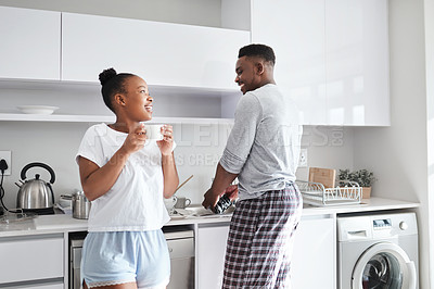 Buy stock photo Shot of a young man washing the dishes while his wife has a cup of coffee at home