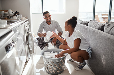 Buy stock photo Shot of a happy young couple doing laundry together at home