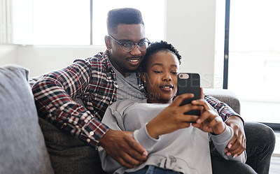 Buy stock photo Shot of a young couple using a cellphone while relaxing on a sofa at home