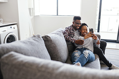 Buy stock photo Shot of a young couple using a cellphone while relaxing on a sofa at home