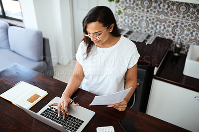 Buy stock photo Shot of a young woman going through paperwork while working from home