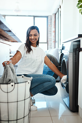 Buy stock photo Shot of a young woman using a washing machine at home