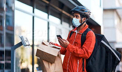 Buy stock photo Shot of a masked man using his cellphone while doing a food delivery