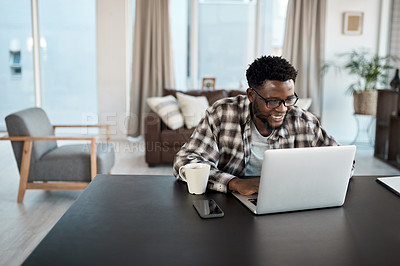 Buy stock photo Shot of a young man working on a laptop at home