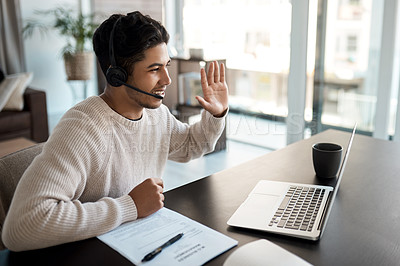 Buy stock photo Shot of a young man wearing a headset while making a video call on a laptop at home