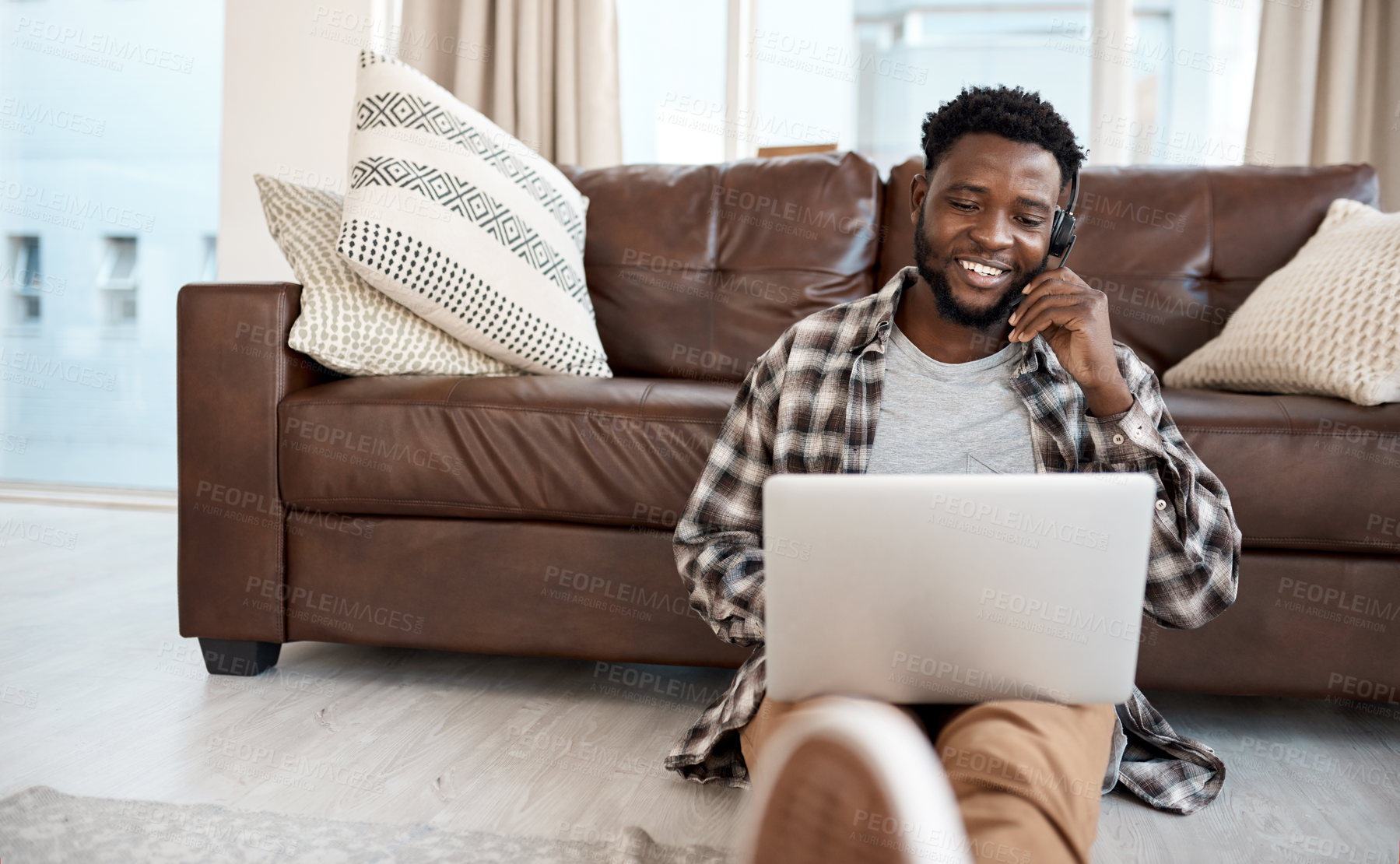 Buy stock photo Shot of a young man wearing a headset while working on a laptop at home