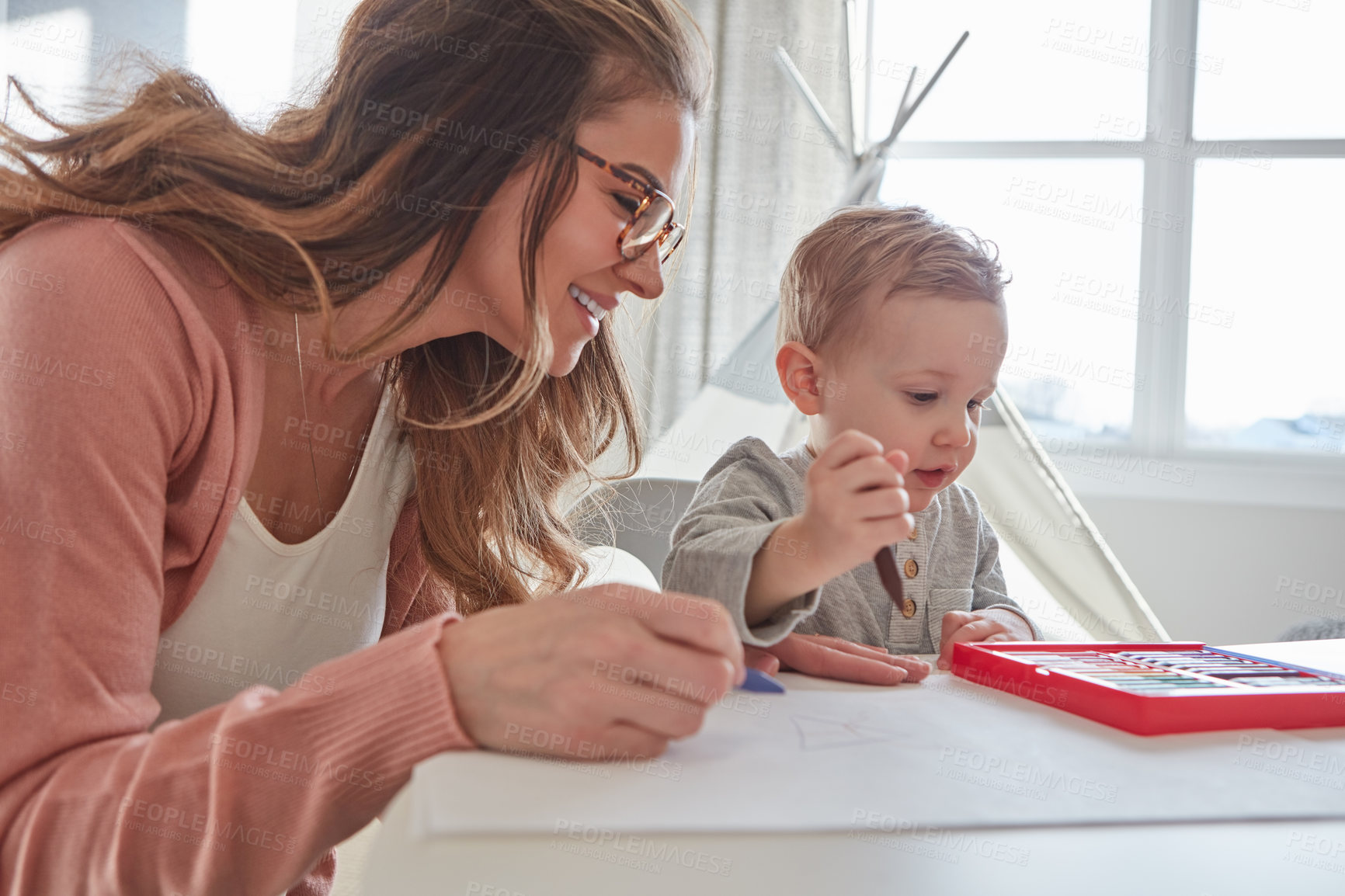 Buy stock photo Shot of a woman and her young son using crayons to draw at home