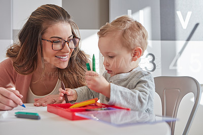 Buy stock photo Shot of a woman and her young son using crayons to draw at home