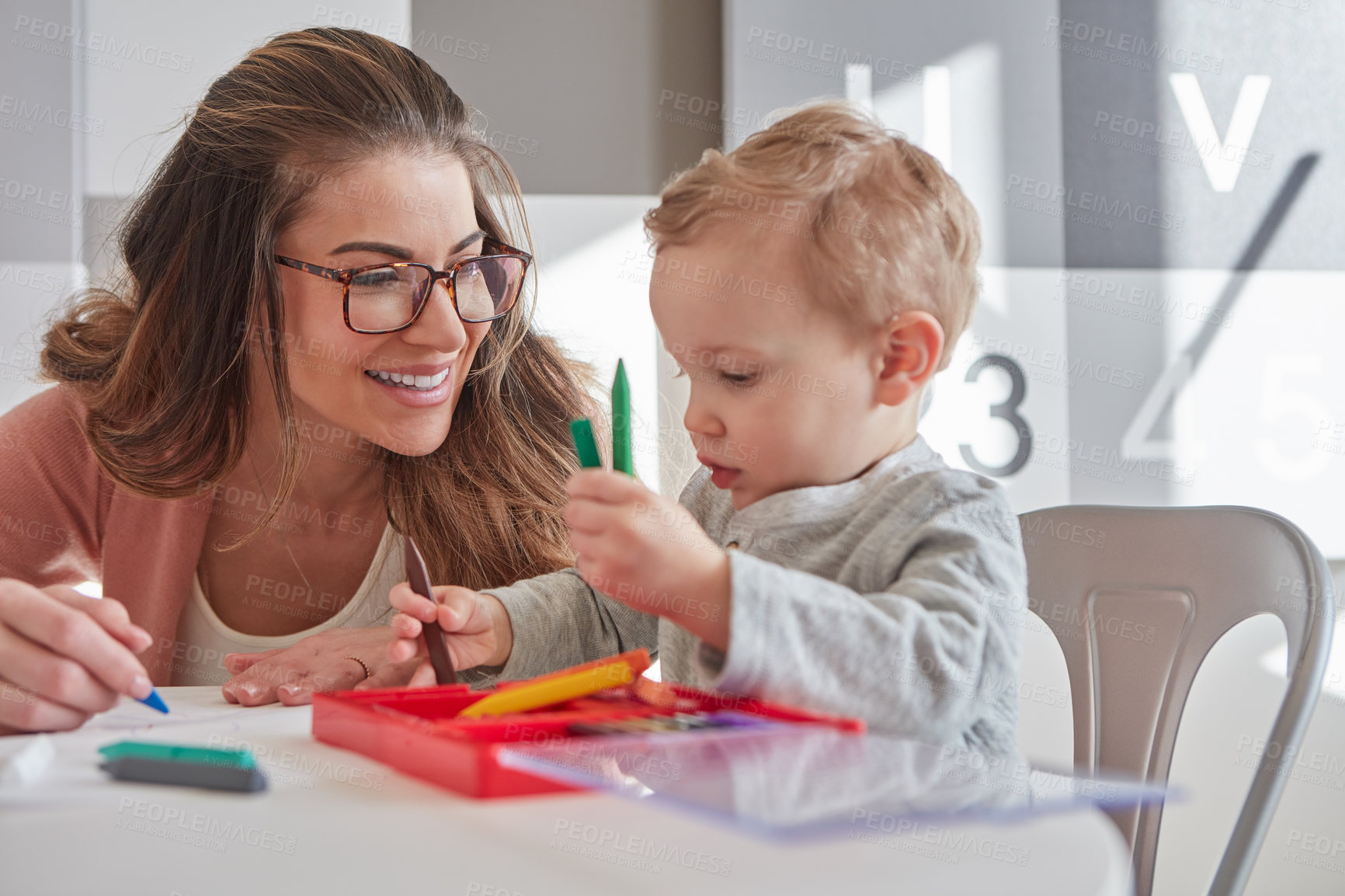 Buy stock photo Shot of a woman and her young son using crayons to draw at home