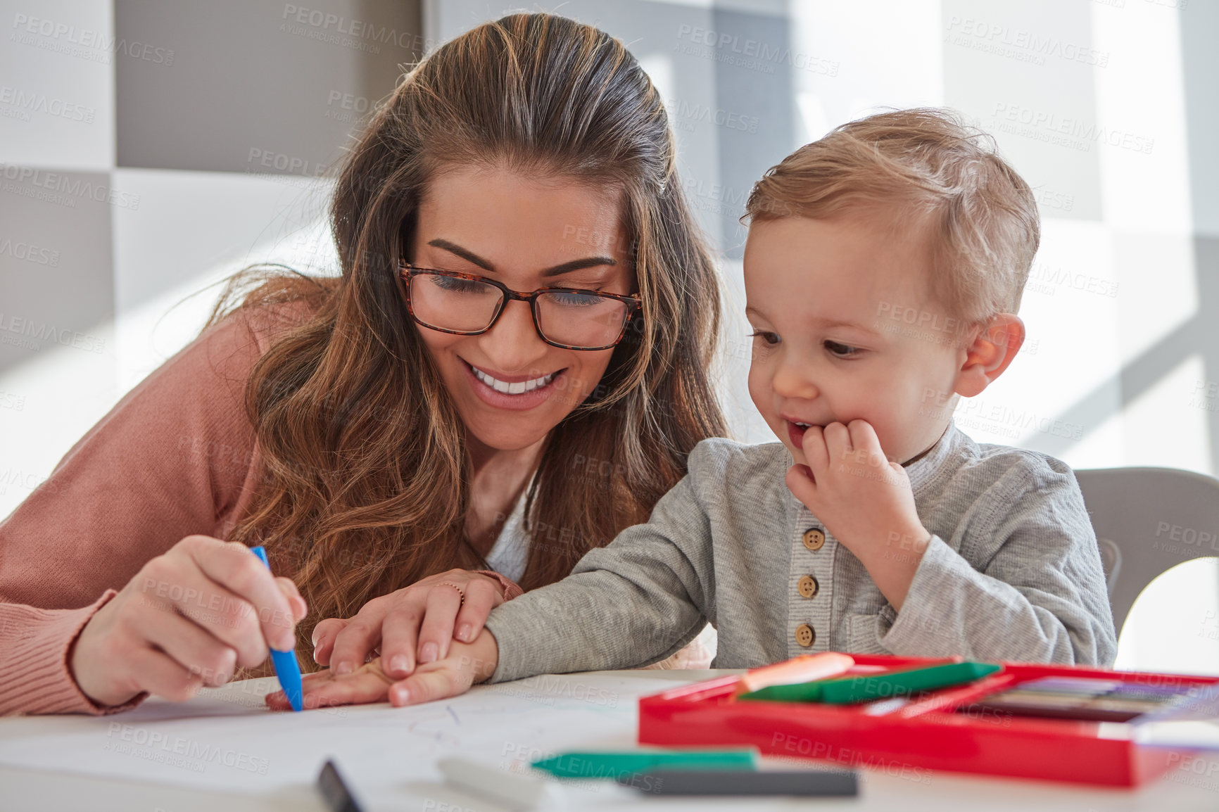 Buy stock photo Shot of a woman and her young son using crayons to draw at home