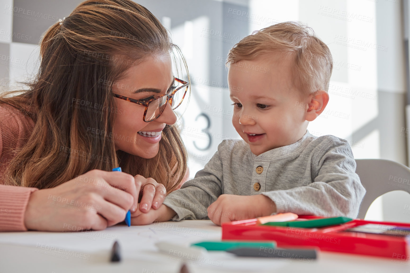 Buy stock photo Shot of a woman and her young son using crayons to draw at home