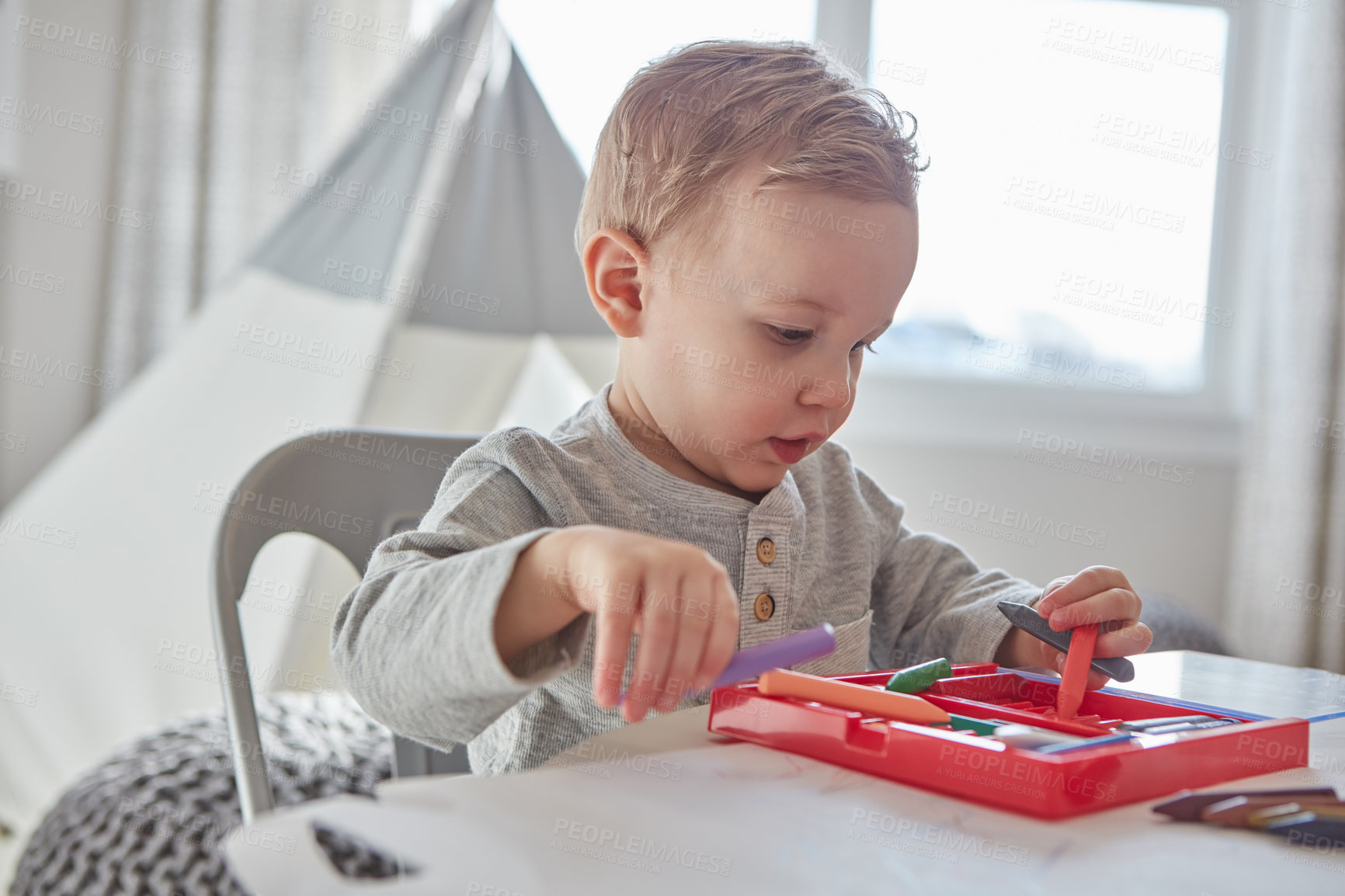 Buy stock photo Cropped shot of a little boy playing with his crayons at home