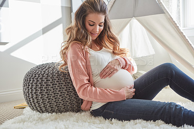 Buy stock photo Shot of a pregnant woman touching her belly while sitting at home