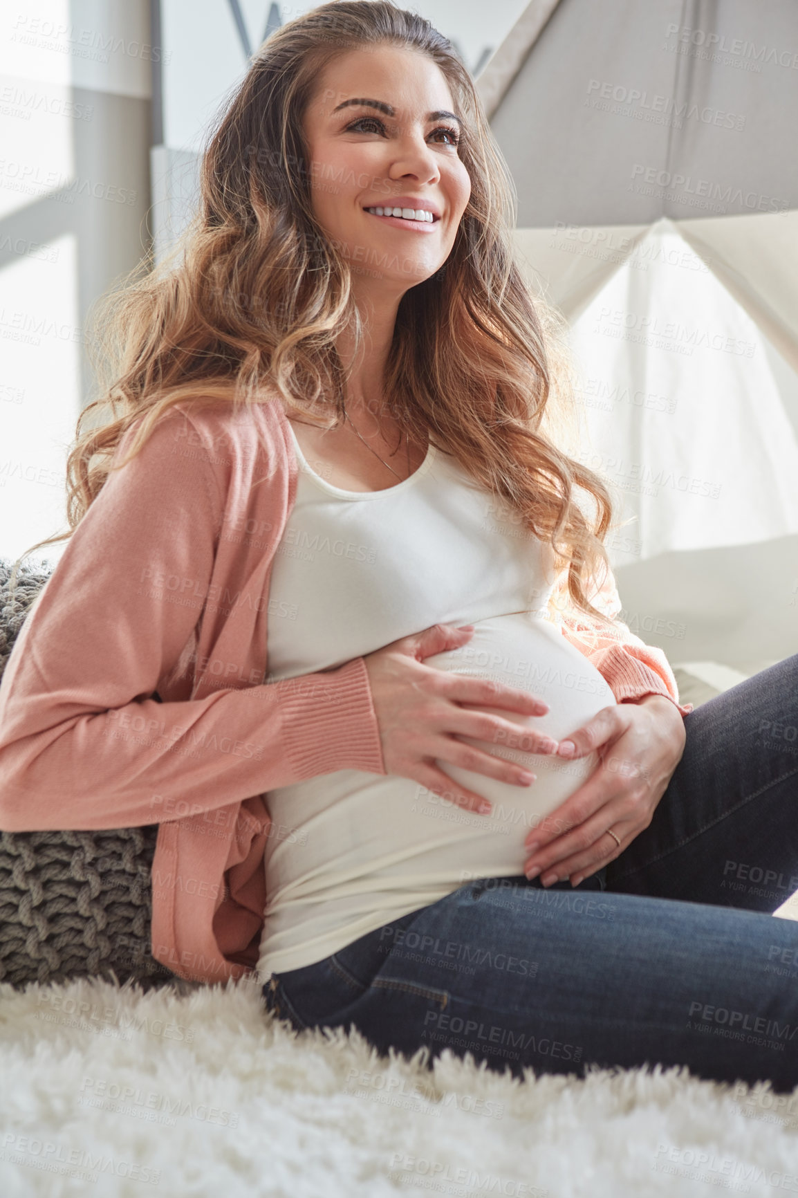 Buy stock photo Shot of a pregnant woman touching her belly while sitting at home