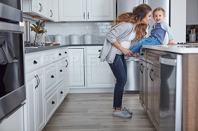 Buy stock photo Shot of a pregnant woman and her son spending time together in the kitchen at home