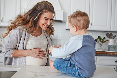 Buy stock photo Shot of a pregnant woman and her son spending time together in the kitchen at home